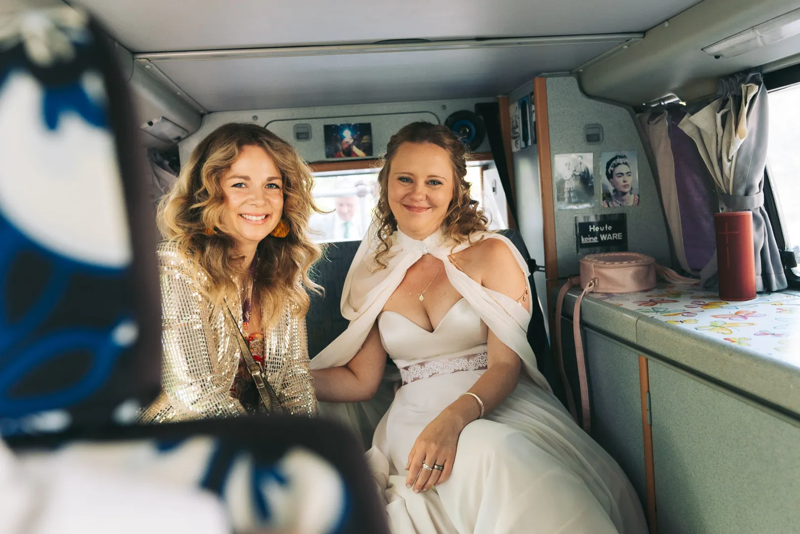 hochzeitsfotograf-wolfsburg-braut-und-trauzeugin-im-auto Eine Braut und ihre Trauzeugin sitzen vor der Hochzeit zusammen im Auto und lächeln nervös in die Kamera