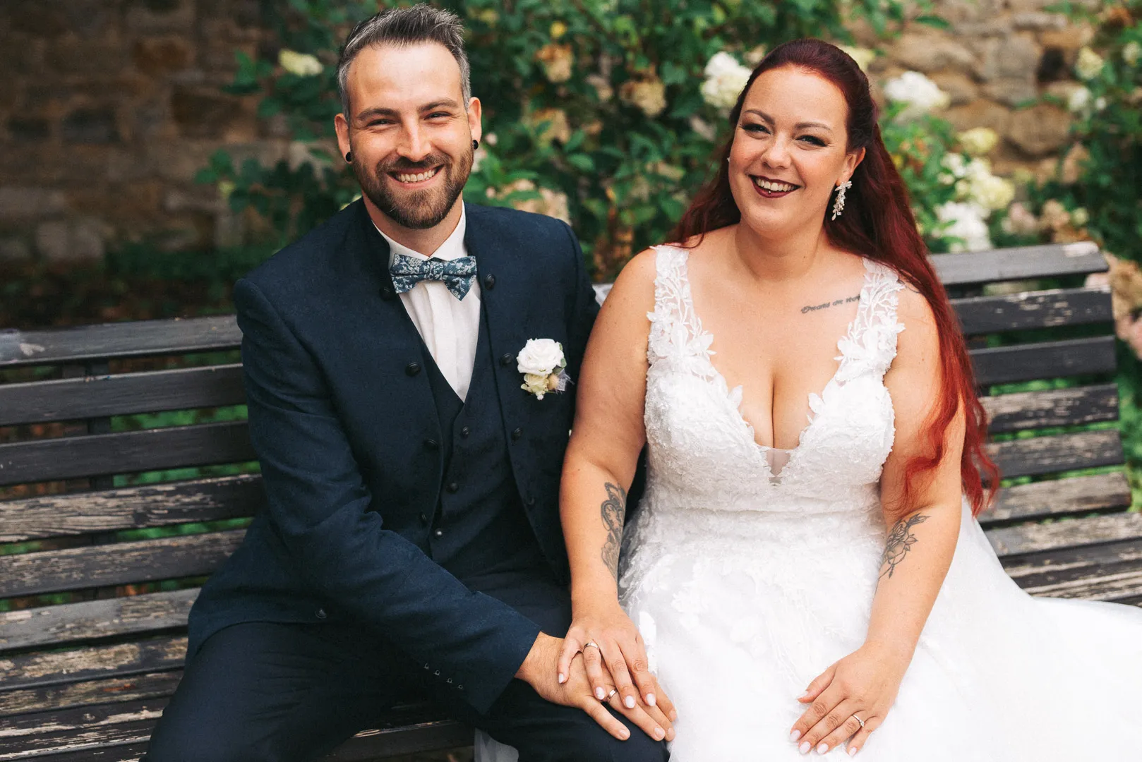hochzeitsfotograf-wolfsburg-brautpaar-auf-parkbank Ein Brautpaar sitzt auf einer Parkband in Fallersleben und strahlt in die Kamera