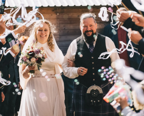 hochzeitsfotograf-wolfsburg-brautpaar-spalier Ein strahlendes Brautpaar marschiert nach der Trauung durch ein Spalier von Gästen. Es werden Seifenblasen gepustet und Wedding Wands geschwenkt