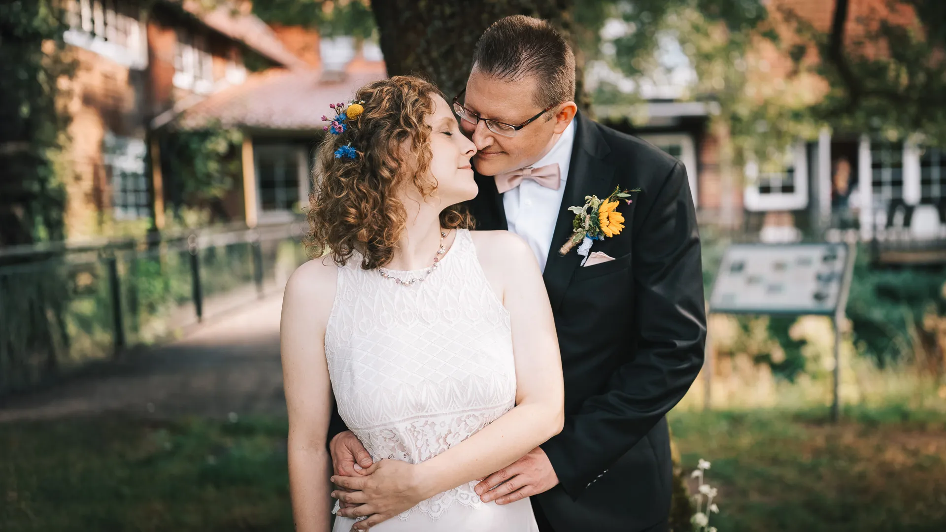 hochzeitsfotograf-wolfsburg-brautpaar-verliebt-unter-baum Ein verliebtes Brautpaar steht unter einem Baum an der Brackstedter Mühle nahe Wolfsburg und umarmt sich zärtlich