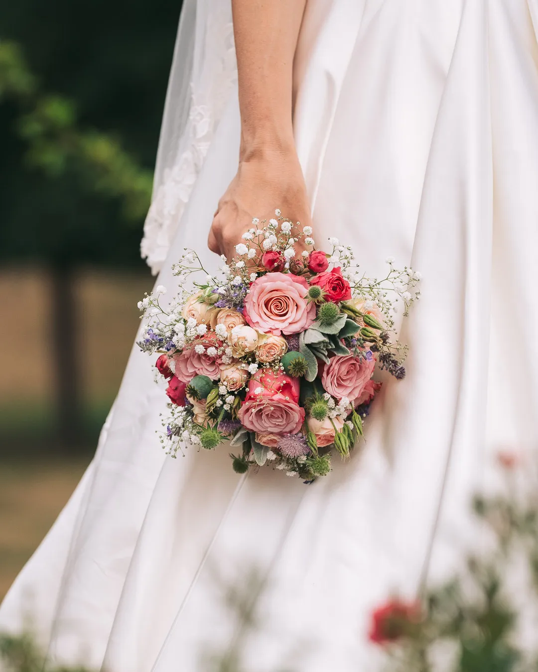 hochzeitsfotograf-wolfsburg-brautstrauss Detailaufnahme eines Brautstraußes, die Braut im weißen Kleid hält die Blumen in der Hand
