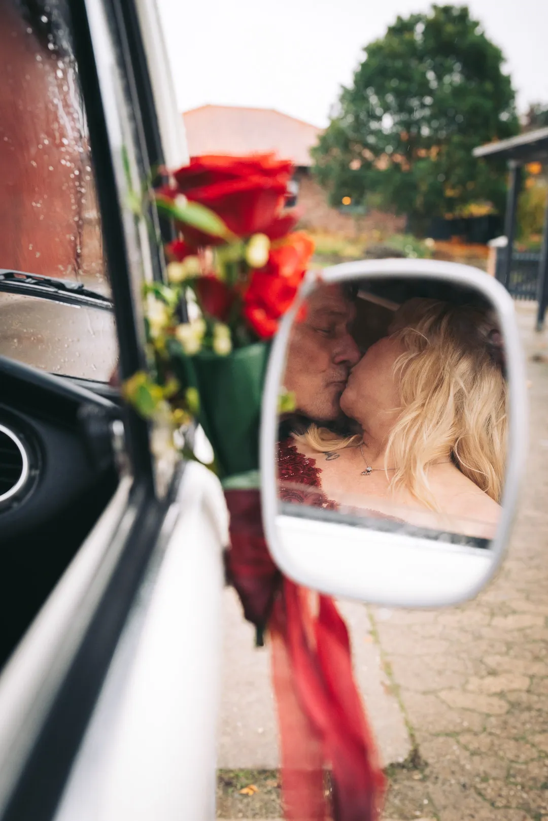 hochzeitsfotograf-wolfsburg-kuss-seitenspiegel Im Außenspiegel eines VW T1 Bus ist ein Brautpaar zu sehen, das sich küsst