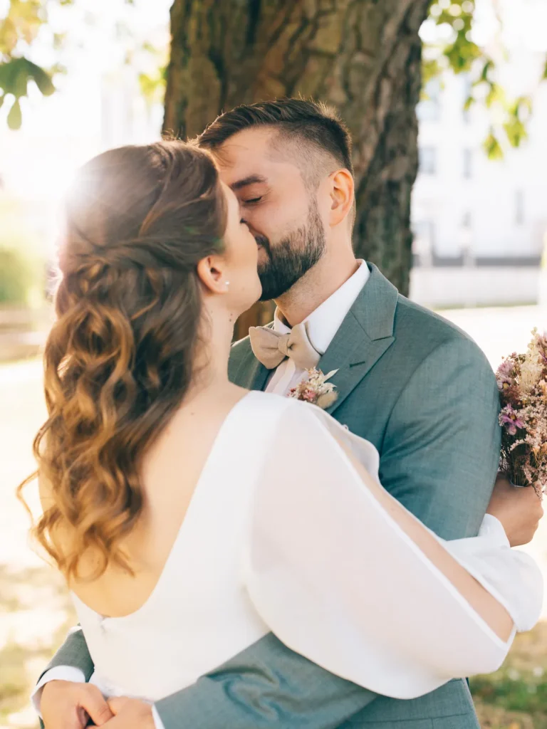 Ein Brautpaar küsst sich unter einem Baum bei einer Hochzeit in Wolfsburg