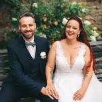 Brautpaar Christin und Marcel sitzt strahlend auf einer Parkbank bei einer Hochzeit in Wolfsburg