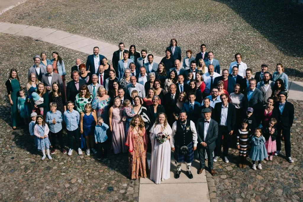 Gruppenfoto des Brautpaares mit den Hochzeitsgästen auf dem Hof des FarmInn Wittingen