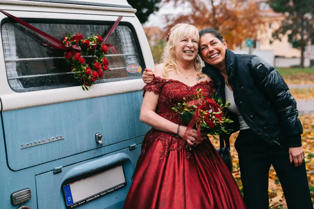 Braut und Trauzeugin posieren vor der Hochzeit im Schloss Fallersleben in Wolfsburg an einem VW Bus